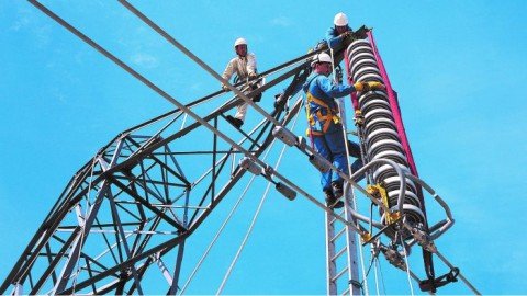 trabajadores instalando aisladores en una torre eléctrica